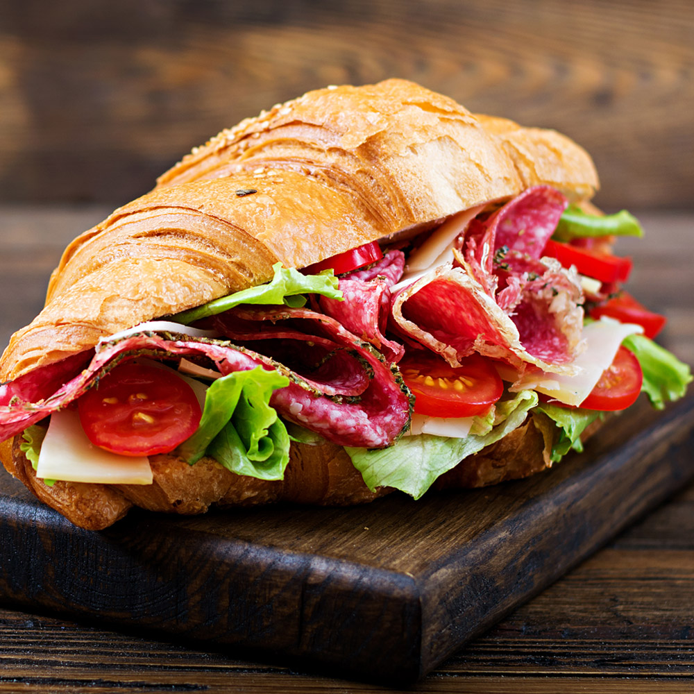 A salami sandwich on a wooden cutting board