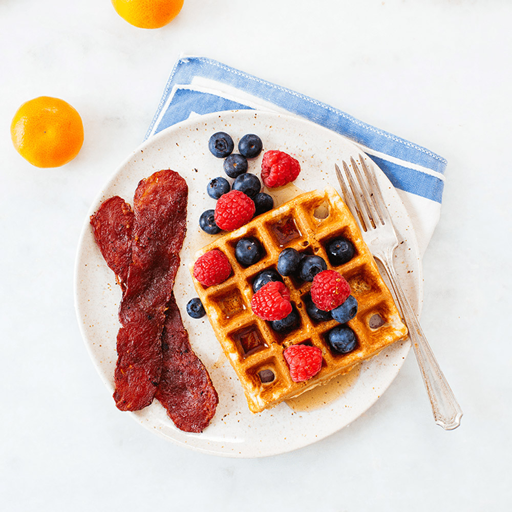 applegate naturals uncured turkey bacon cooked on plate with waffles and syrup blueberries and raspberries and oranges