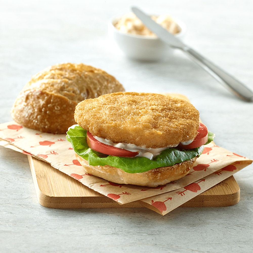 applegate naturals chicken patties cooked on sandwich with lettuce and tomato on cutting board