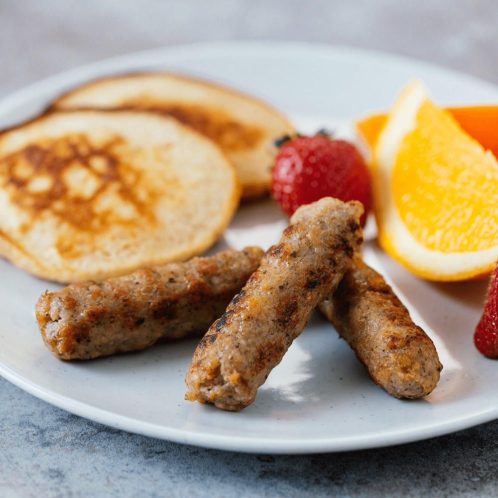 applegate naturals chicken & maple breakfast sausage links cooked on plate with pancakes and fruit