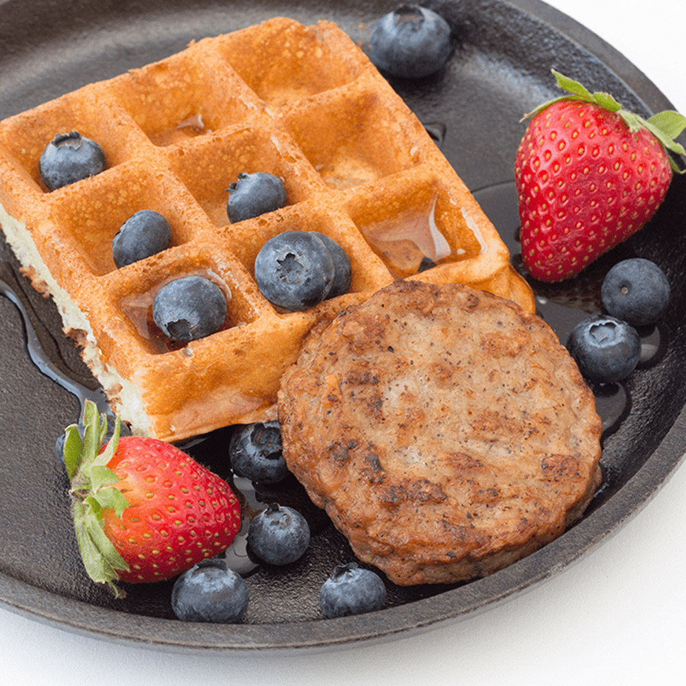 applegate naturals chicken & maple breakfast sausage patties cooked on plate with waffle and blueberries and strawberries