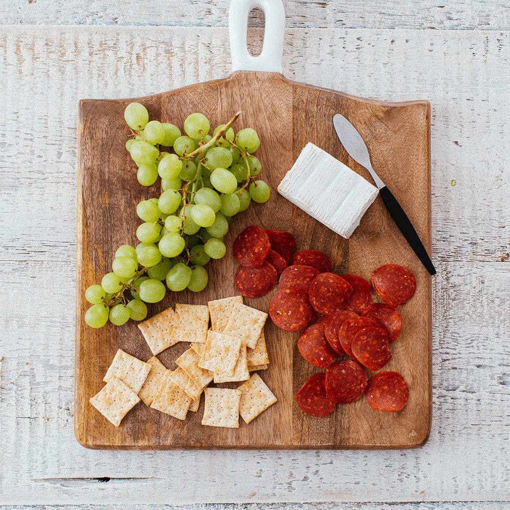 applegate naturals uncured turkey pepperoni on cutting board with grapes and cheese and crackers