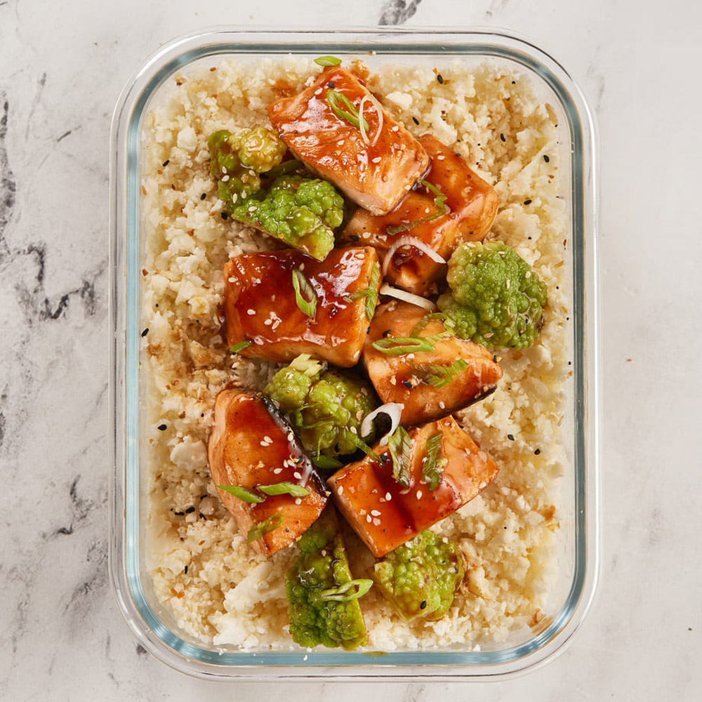 Salmon and broccoli over rice in a glass lunch container
