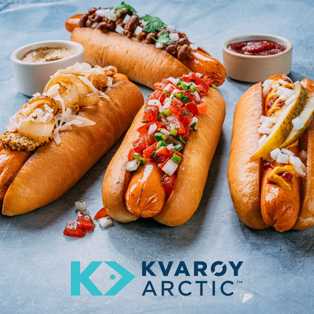 Four hot dogs with toppings on a blue background