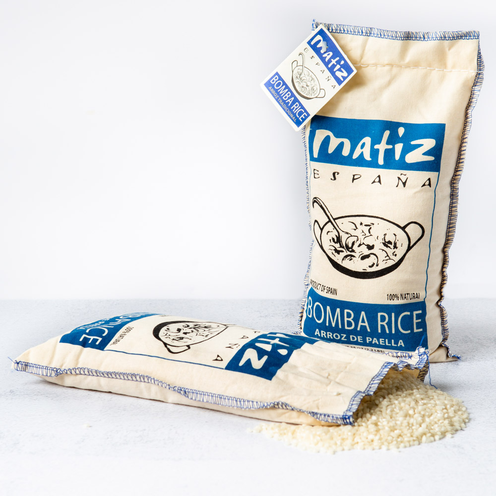 Two bags of Matiz España bomba paella rice next to a pile of rice