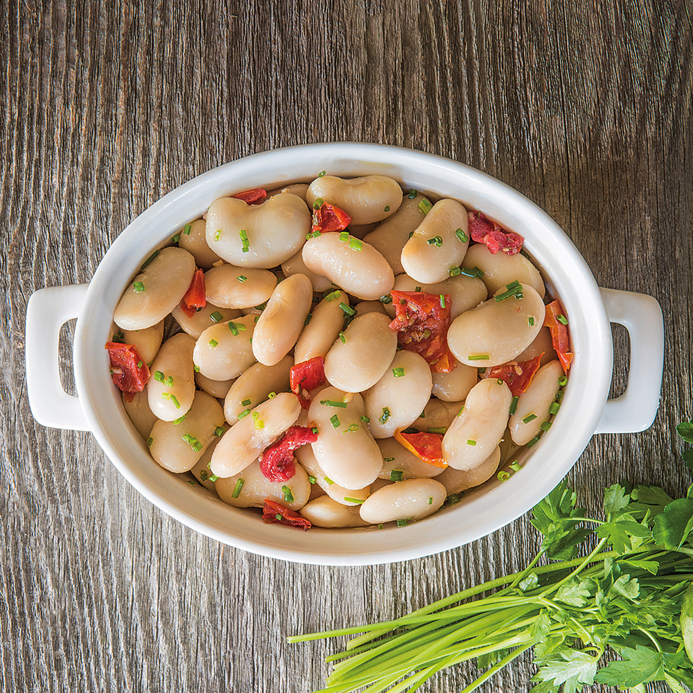 Bowl of Divina gigandes beans in brine with a wood background