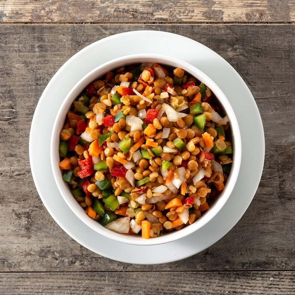 Lentil salad with peppersonion and carrot in a bowl on wooden table