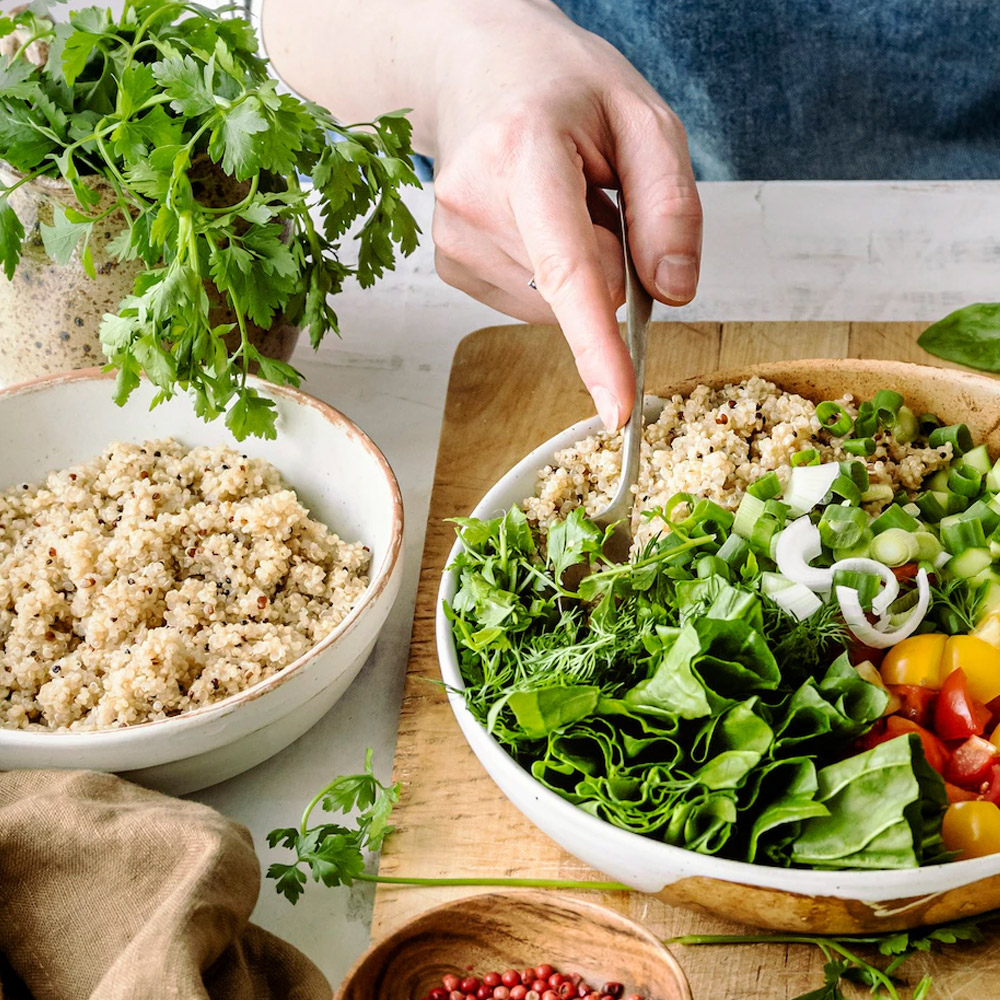 A bowl of quinoa next to a bowl of salad