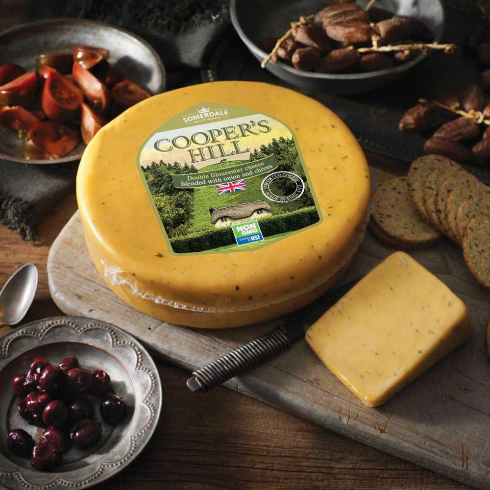Wheel of Somerdale Cooper's Hill Double gloucester cheese on a wood board surrounded by fruit and crackers