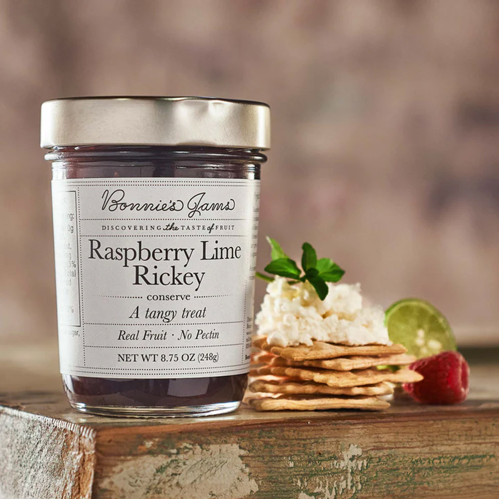 A jar of Bonnie's Jams Raspberry Lime Rickey on a wood board next to cheese and crackers
