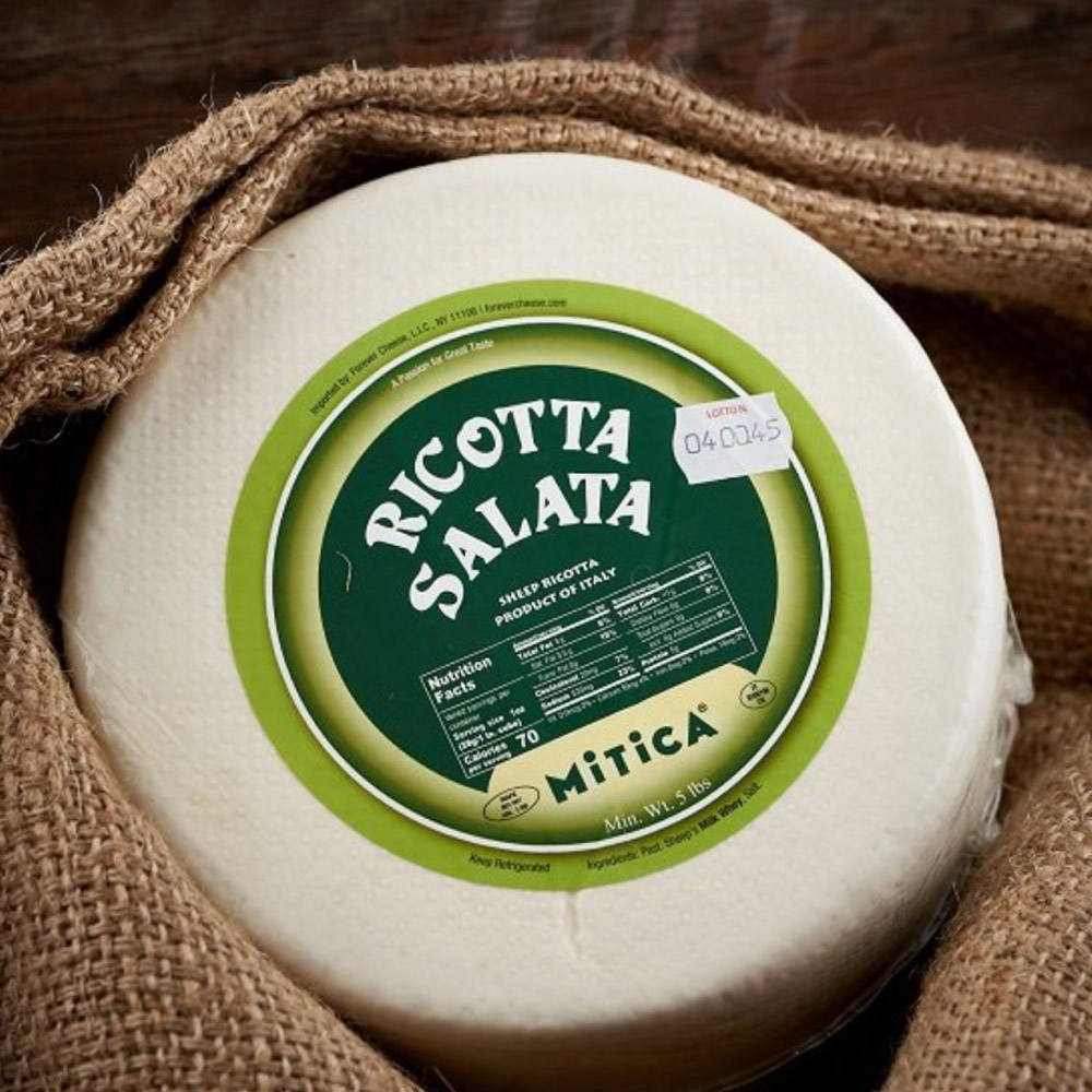 A wheel of Mitica Ricotta Salata surrounded by burlap