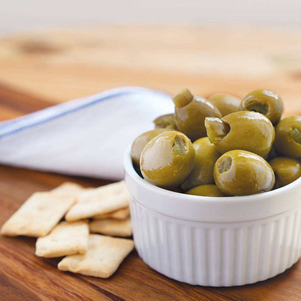 divina green olives stuffed with jalapeño in white bowl with crackers