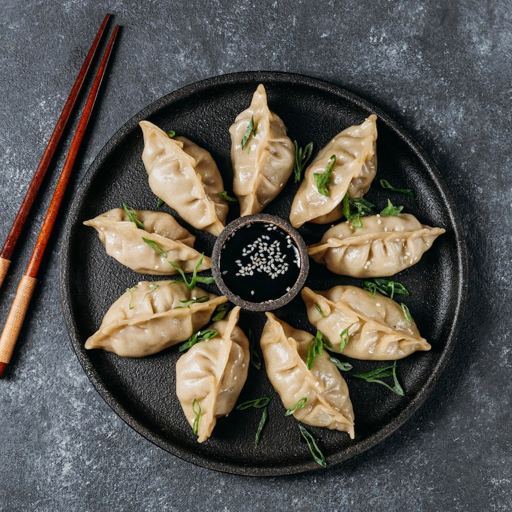 Plate of Japenese dumplings with a bowl of sauce in the middle