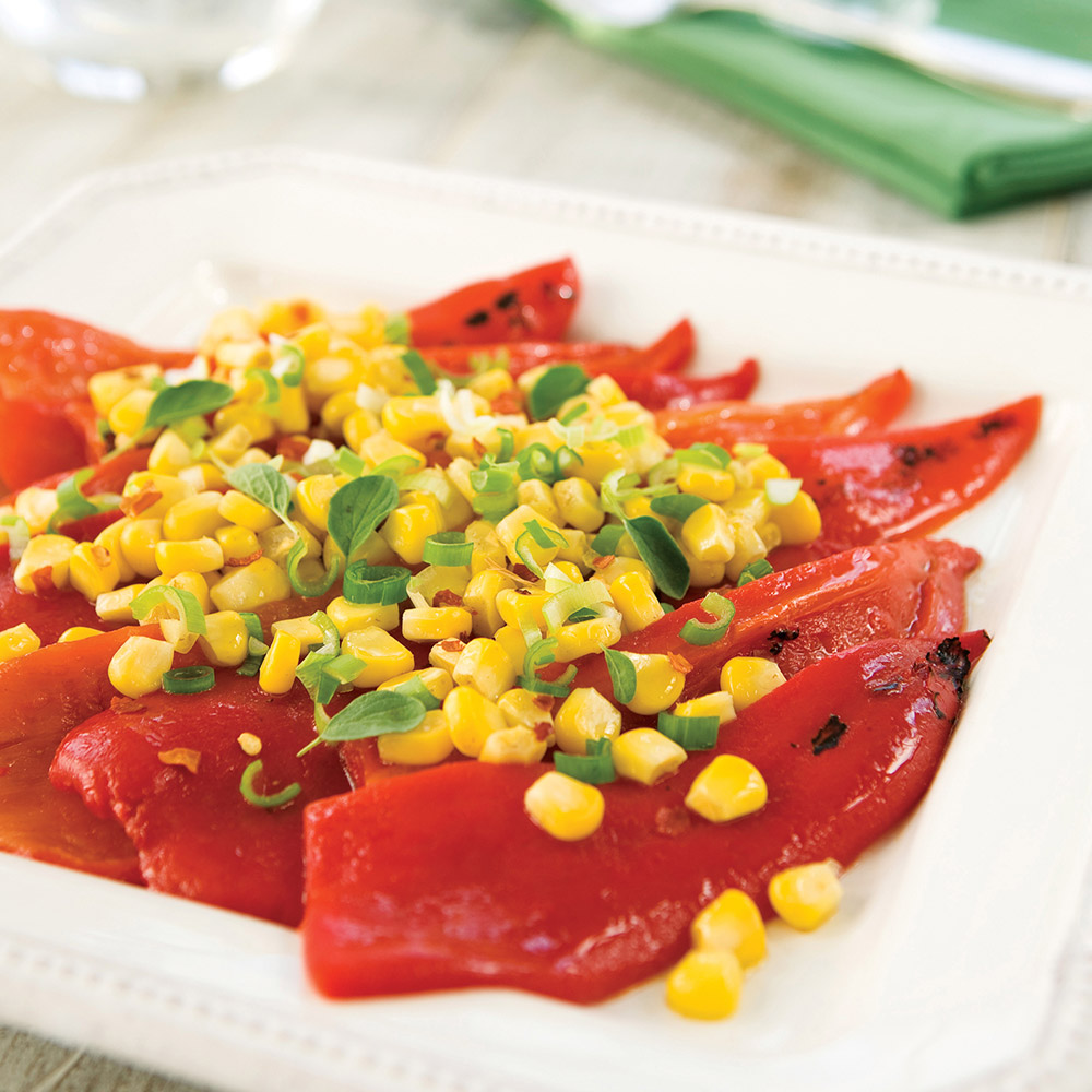 Divina Organic Roasted Red Peppers on a plate tipped with roasted corn and herbs