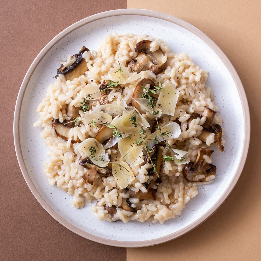 Plate of mushroom risotto on a dual tone brown background