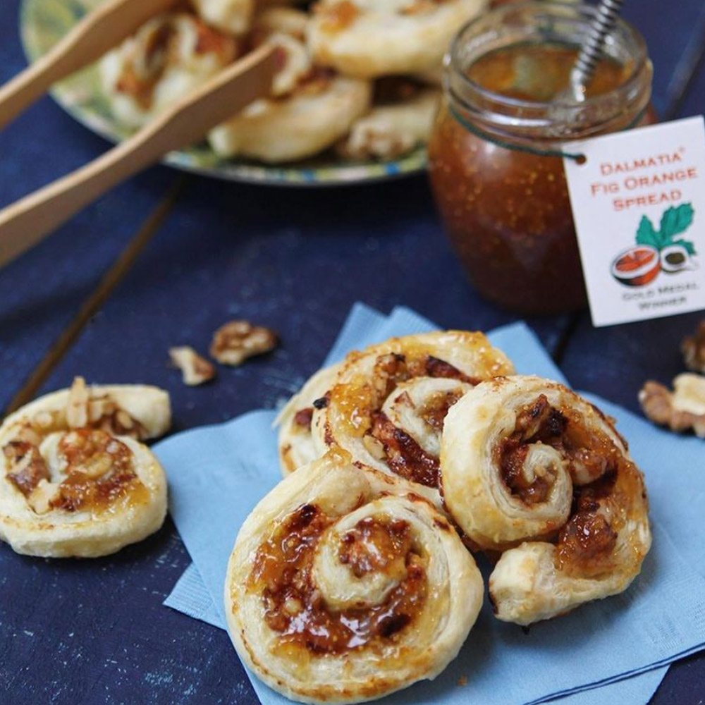 Pinwheel pastries filled with fig orange spread in front of a jar of fig orange spread