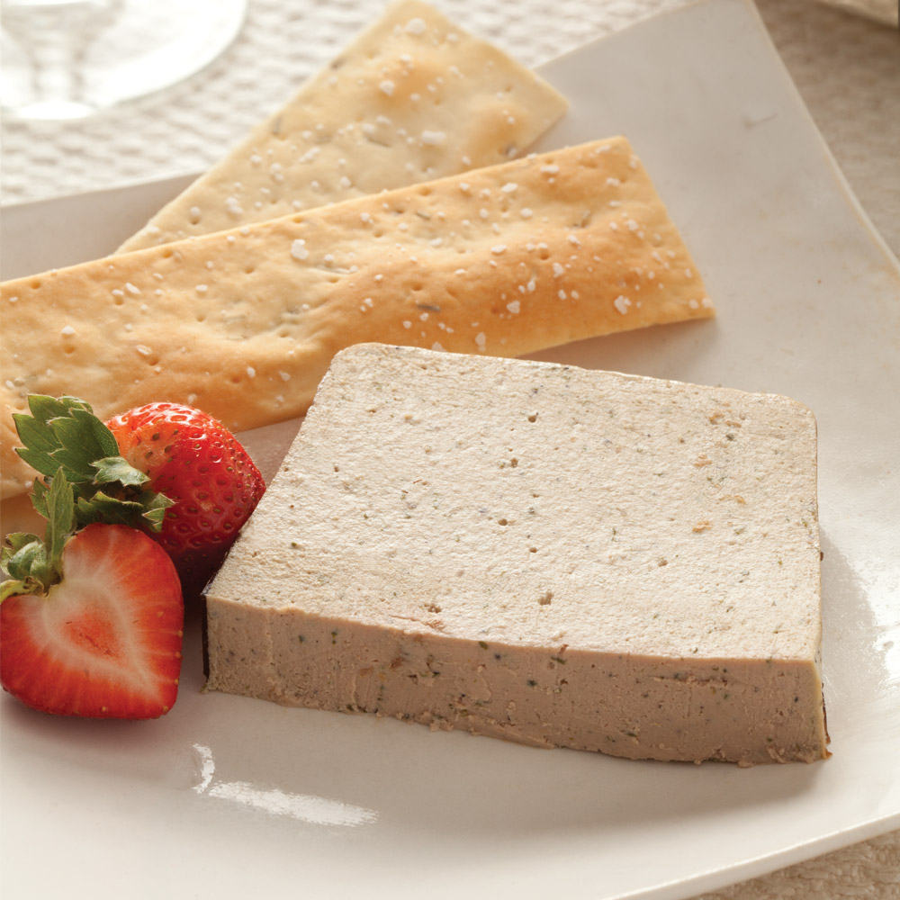 A slice of pate on a plate with a strawberry and two flatbread crackers
