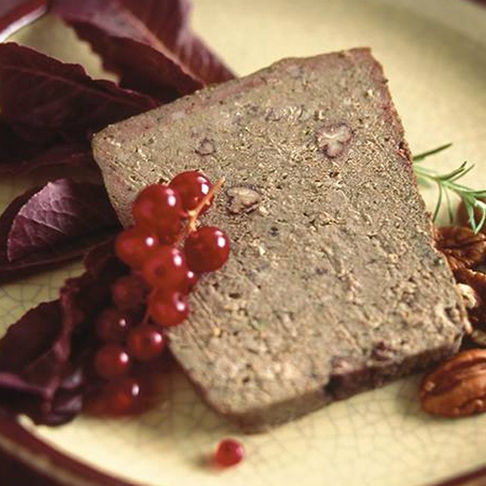 A slice of pate on a plate with some red berries