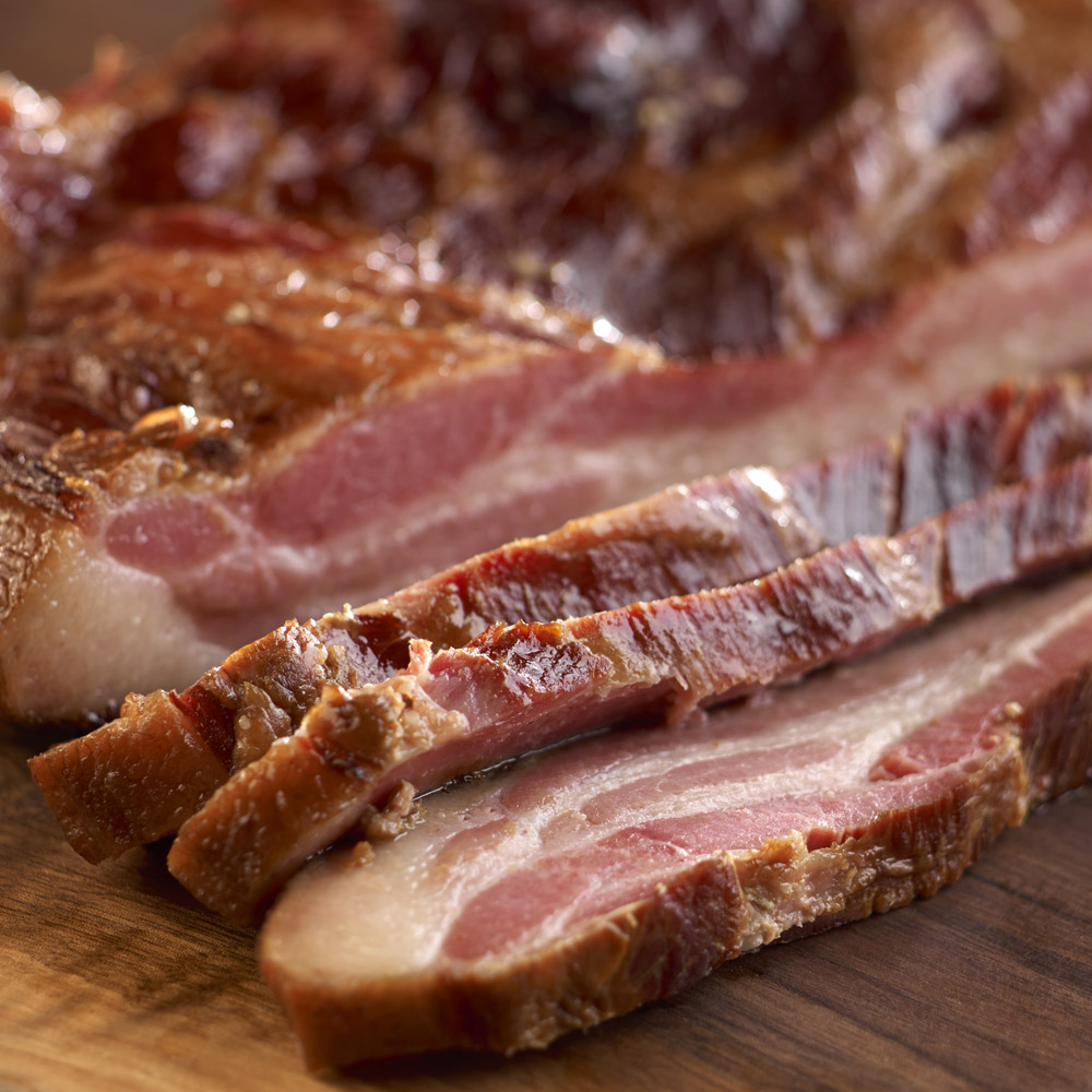 nueske's applewood smoked slab bacon sliced on cutting board