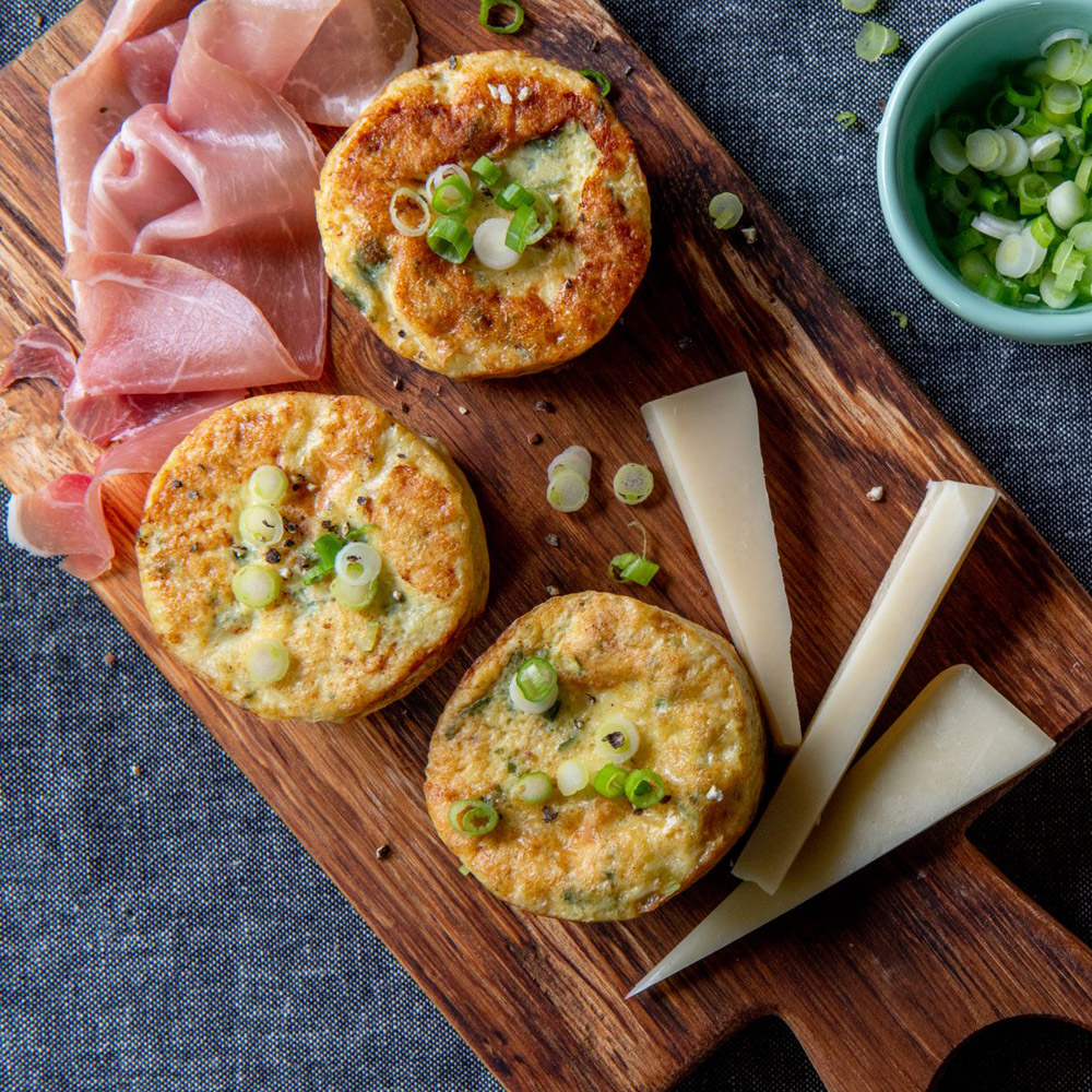 Les trois petits cochons egg bite with prosciutto and gruyere prepared on wood cutting board