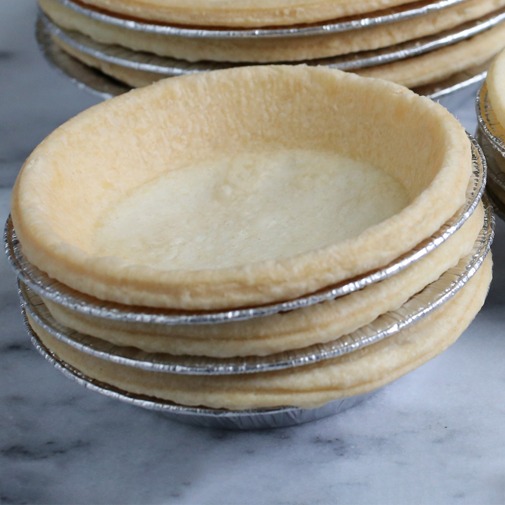Dufour Pastry Kitchens 3 inch traditional tart shells in metal tins on a marble counter