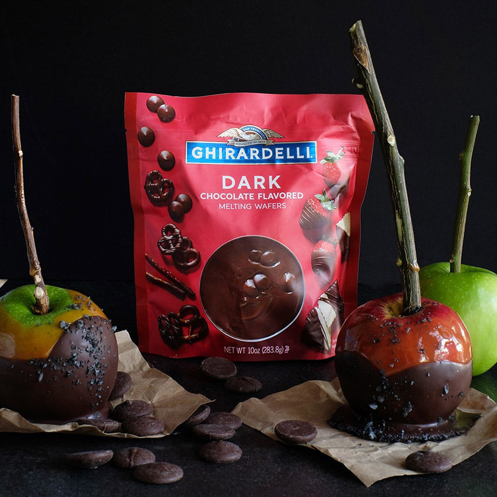 A bag of chocolate wafers next to apples dipped in chocolate