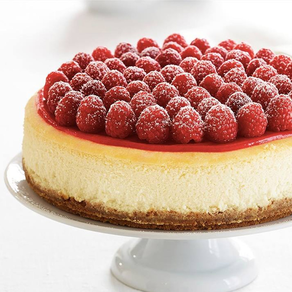 A white chocolate raspberry cheesecake on a cake stand