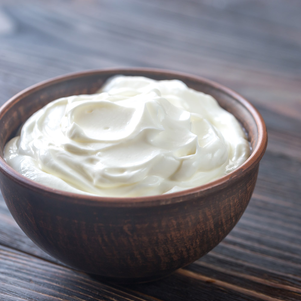 A bowl of greek yogurt on a wood surface