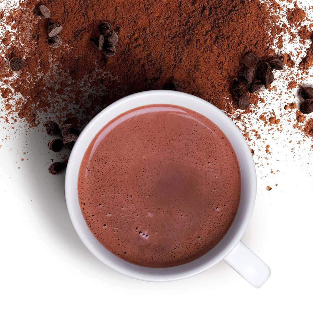 A mug of hot cocoa surrounded by cocoa powder